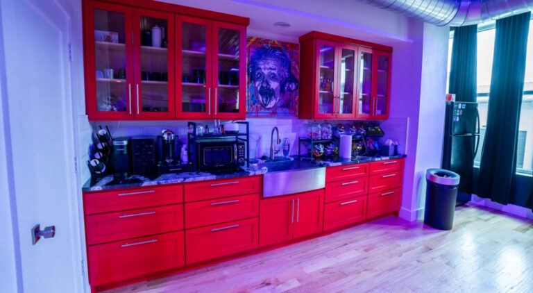 Sanctum Studio kitchen and amenities area with bold red cabinetry, countertops, and modern appliances available for studio rental clients in Roanoke TX