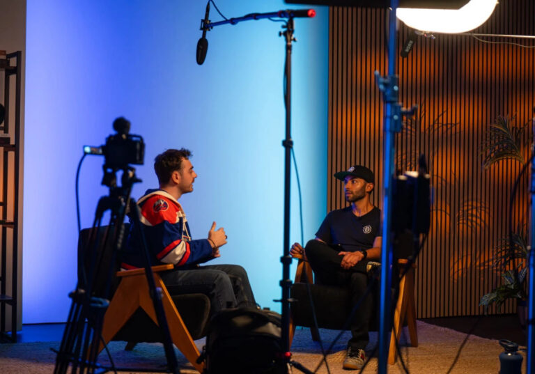 Two creators recording a podcast interview at Sanctum Studio in Roanoke TX with camera, boom mic, and professional studio lighting