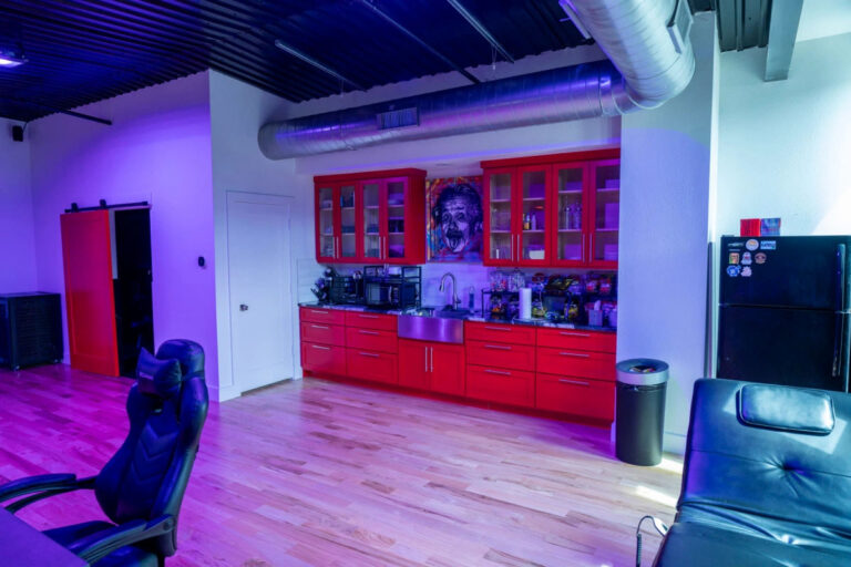 Sanctum Studio secondary production room with red cabinetry, equipment storage, hardwood floors, and gaming chair in Roanoke TX