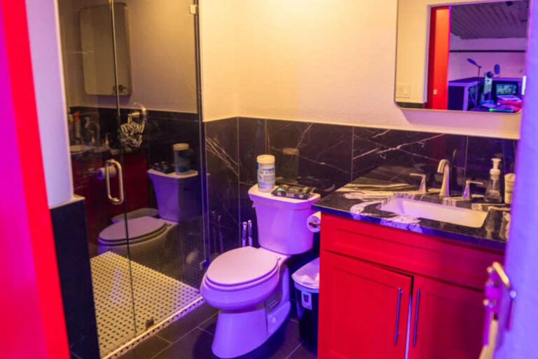 Private restroom with modern tile and red accent finishes inside Sanctum Studio rental space in Roanoke TX